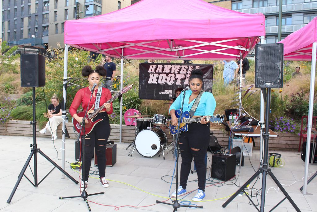 A group of people playing music in front of a pink tent.