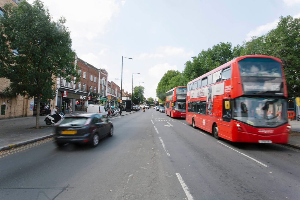 A red double decker bus driving down a city street.